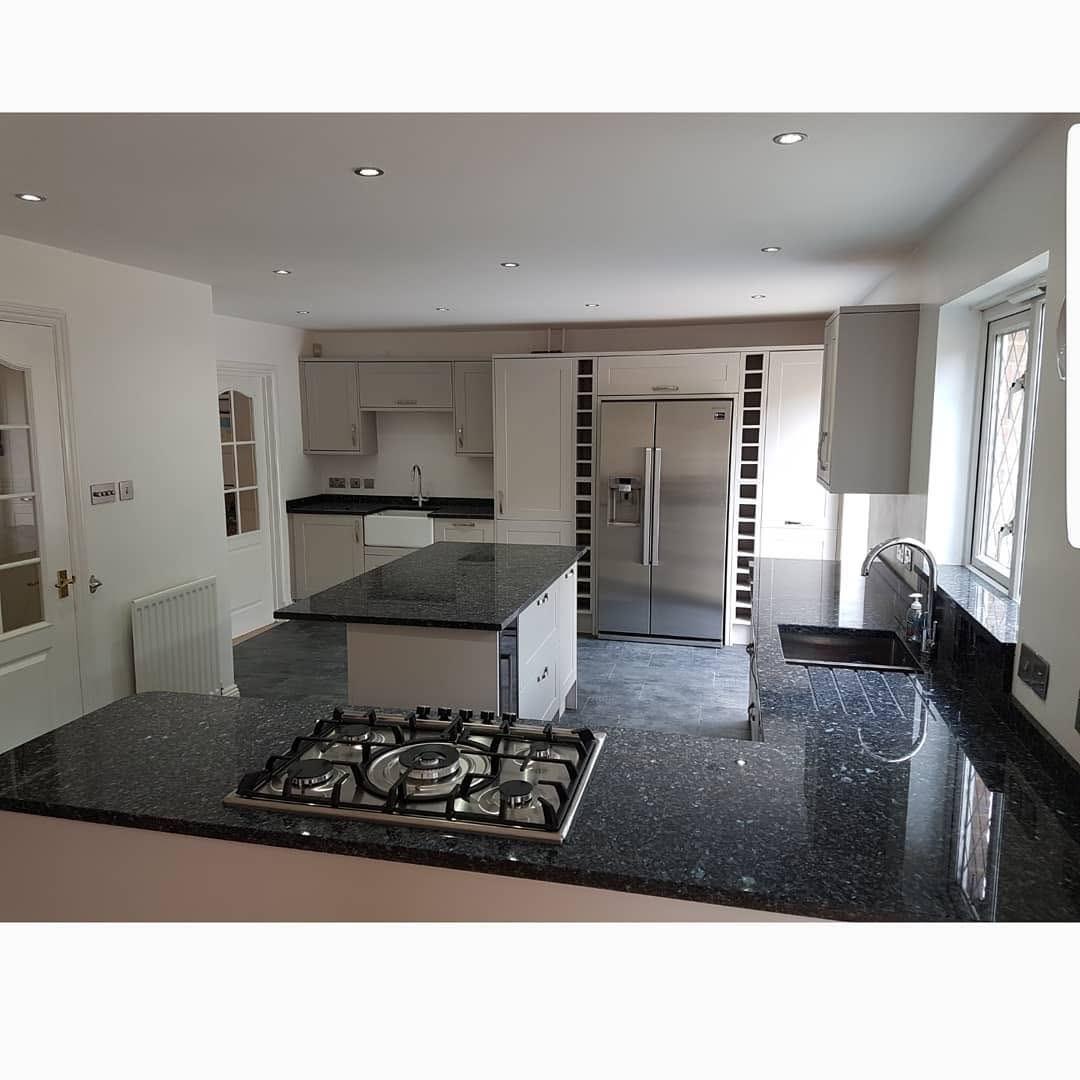 Fitted kitchen with granite worktops and hob on the island by ADO Builders, Surrey