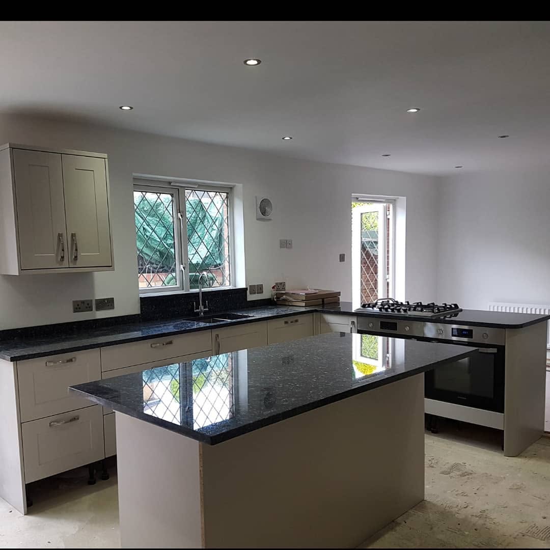 Kitchen with black granite worktops and island in Surrey by ADO Builders