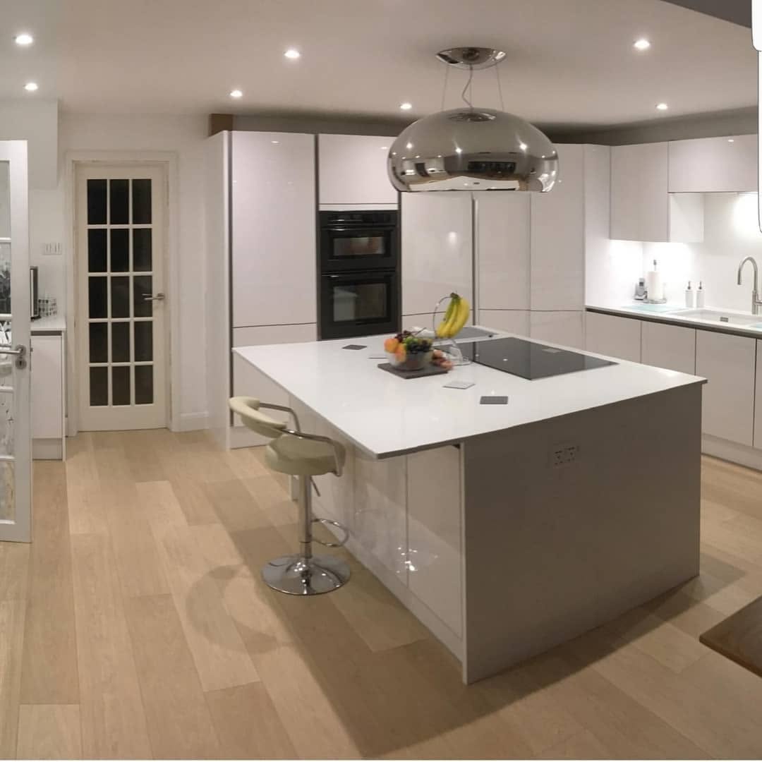 Open-plan kitchen with island and timber flooring in Surrey by ADO Builders