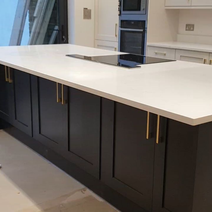 Kitchen island with dark shaker cabinets and brass handles in Surrey by ADO Builders